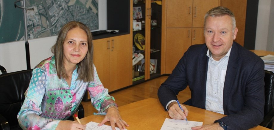 Frau Biljana Pesova und Bürgermeister Peter Burger sitzen an einem Konferenztisch und unterzeichnen den Pachtvertrag.