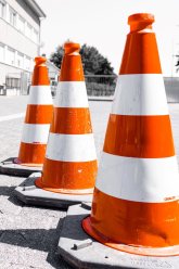 Drei Leitkegel auf grauem Pflaster.