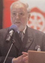 Jean-Pierre Davot steht an einem Mikrofon. Im Hintergrund ist verschwommen das Gernsheimer Wappen zu sehen.