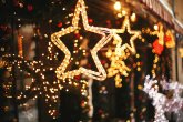 Weihnachtsbeleuchtung mit goldenen Sternen und Tannenzweigen mit roten und goldenen Kugeln.