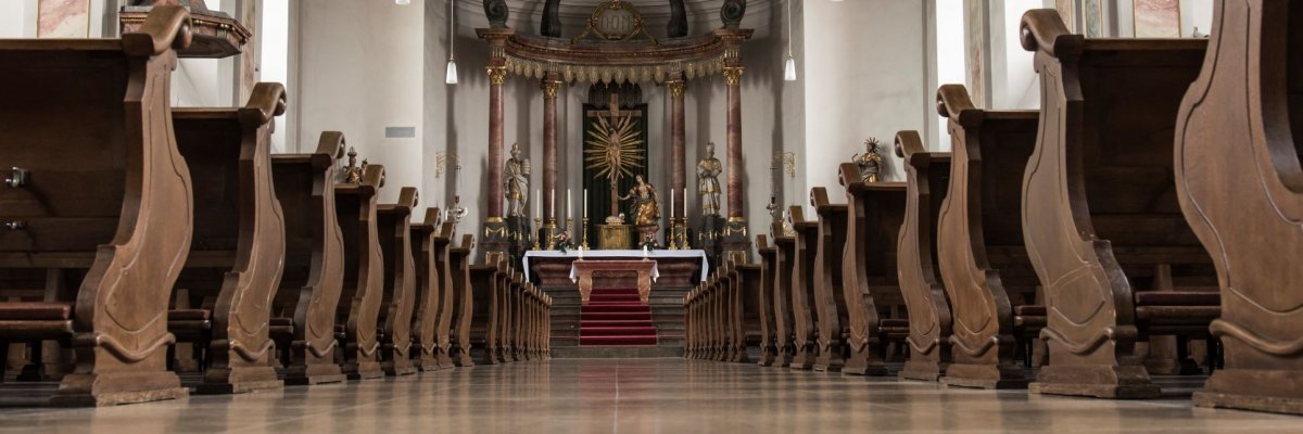 Bild des Innenraums der Pfarrkirche Sankt Maria Magdalena in Gernsheim aus Froschperspektive. Links und rechts die Bankreihen. Blick auf den Altar.