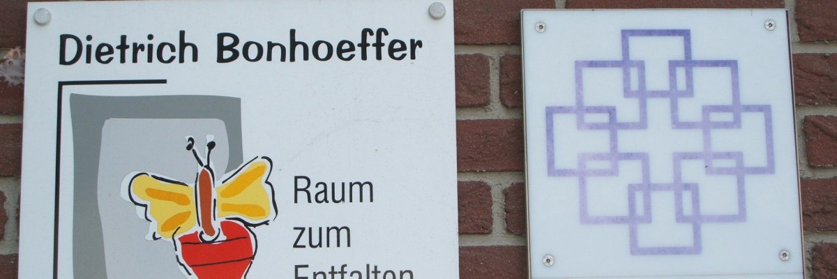 Es ist das Logo der evangelischen Dietrich-Bonhoeffer-Kindertagesstätte zu sehen. Dieses setzt sich aus grauen Rechtecken und einem gelb/roten Schmetterling mit entsprechenden Schriftzug zusammen.