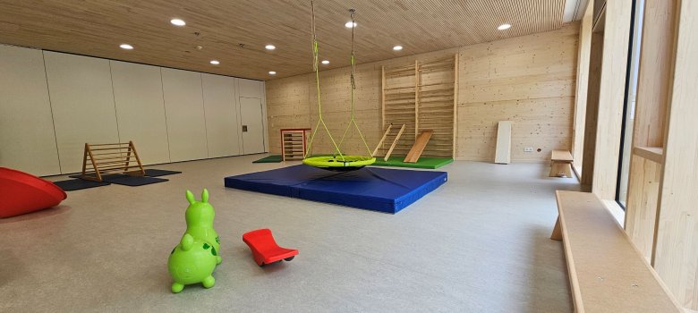Turnraum der Kindertagesstätte Rheinakrobaten mit Spielgeräten: Hüpftier, kleine Wippe, Turnmatte und Nestschaukel