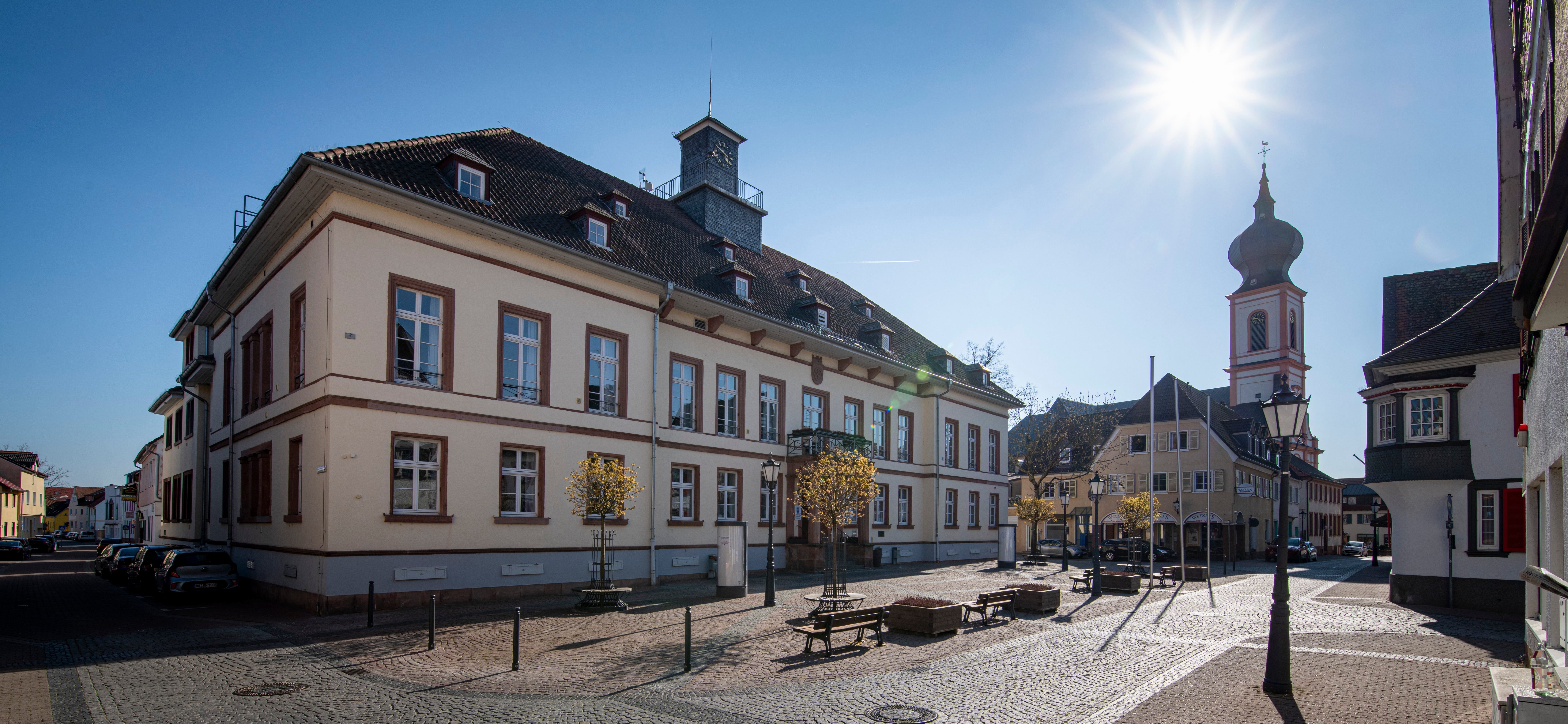 Das Stadthaus Gernsheim aus Richtung der Brasserie aufgenommen. Man sieht die katholische Kirche über der die Sonne scheint.