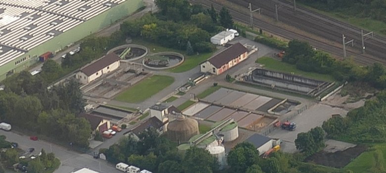 Luftbild der Kläranlage Gernsheim mit den Klärbecken, den Verwaltungsgebäuden und der Bahnstrecke im Hintergrund.