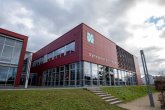 Schräg von links nach rechts verlaufender Blick auf die Front des Gymnasiums mit Hauptblick auf die Verglasung der Mensa und der großen Beschriftung des Gebäudes