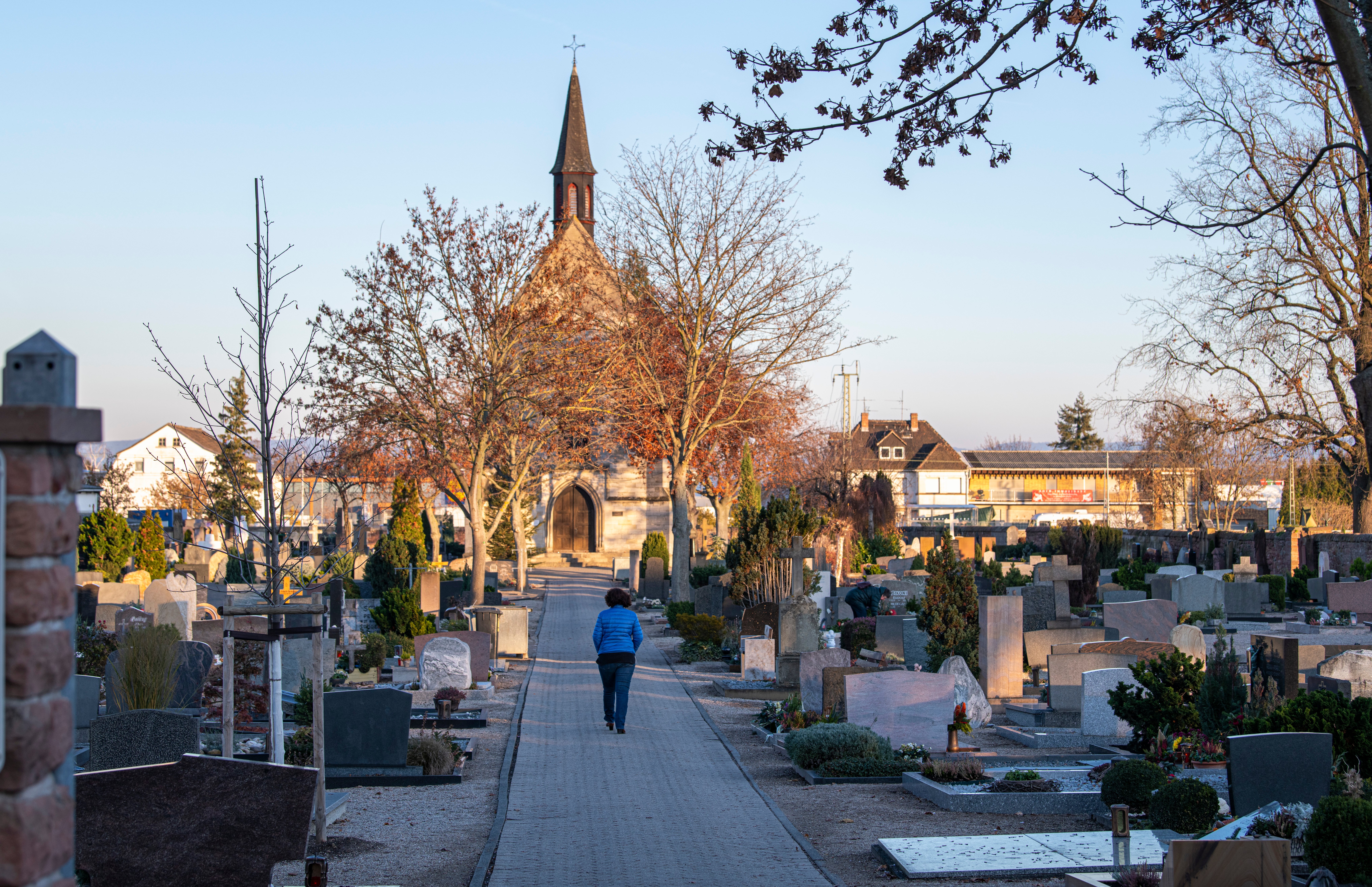 Im Vordergrund befinden sich mehrere Grabsteine des Friedhofs Gernsheim. Im Hintergund befindet sich hinter zwei Bäumen die Michaeliskapelle des Friedhofs.