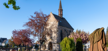 Friedhof mit der Michaeliskapelle im Zentrum davor zahlreiche Grabsteine und Zierbäumchen