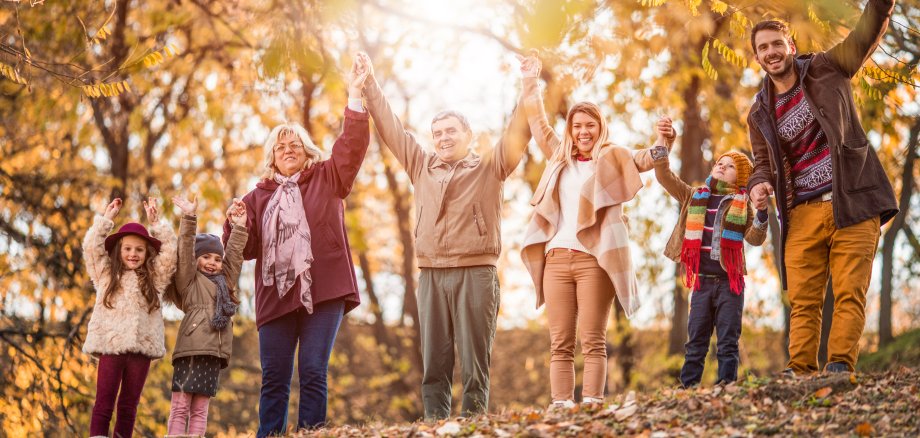 Carefree extended family with arms raised enjoying in autumn day.