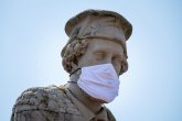 Eine Großaufnahme des Kopfs des Schöffer Denkmals Peter Schöffer trägt eine Mundschutz aus Stoff das Bild entstand zu Beginn der Corona-Pandemie 2020