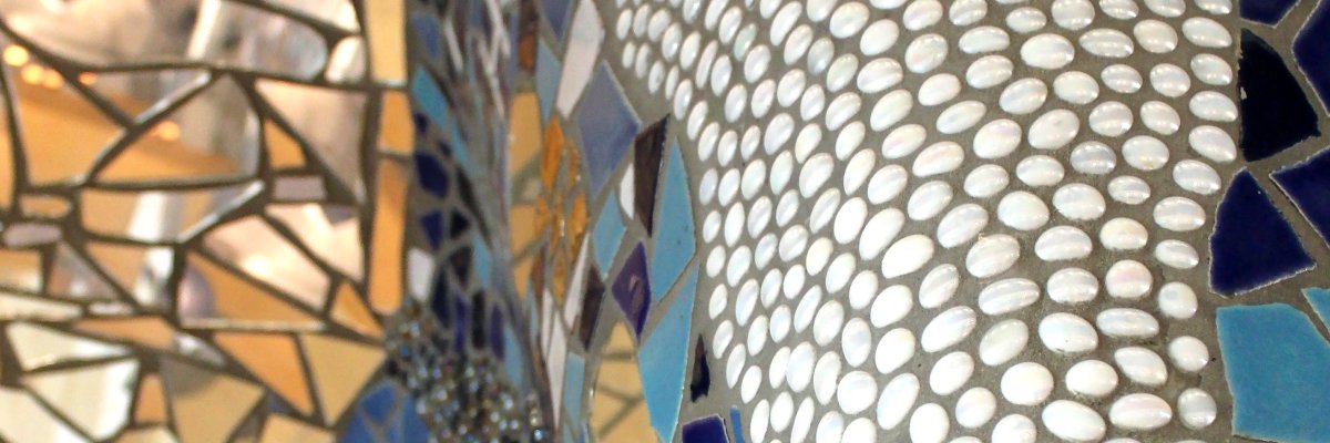 Das Mosaik im Foyer der Stadthalle. Weiße Glassteine bilden eine Art Wasserfall, während blaue Glasnuggets und Mosaikfliesen in Blautönen und Spiegelscherben die weitere Fläche gestalten.