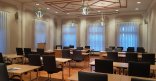 Bürgersaal des Stadthauses. Auf einem Parkettboden stehen in Reihe gestellte Tische mit grauen Stühlen. Im Hintergrund ein Rednerpult mit Mikrofon.