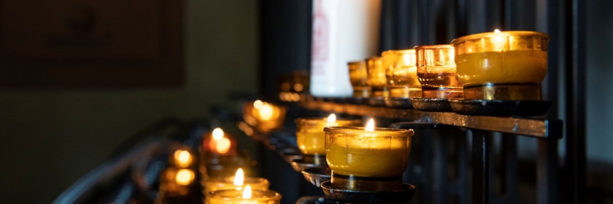 Ein Kerzenschrein mit brennenden Teelichtern und einer großen weißen Stumpenkerze