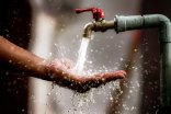 Clean water flows freshly from the tap into the palm of your hand. Focus on the faucet. Aus einem Standrohr läuft Wasser auf eine geöffnete Handfläche