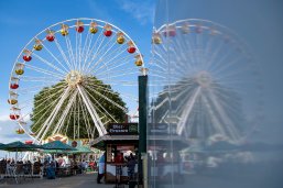 Gezeigt wird das Riesenrad beim Fischerfest Das Bild ist zweigeteilt Links ist das Motiv scharf und rechts als Spiegelung in einem Wagen verwaschen wiederholt