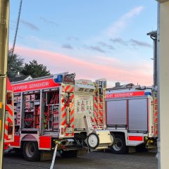 Zwei Feuerwehrfahrzeuge von der Seite. An eines ist ein Schlauch angeschlossen.