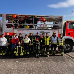 Feuerwehrleute beim Fastnachtsumzug vor einem Feuerwehrfahrzeug.