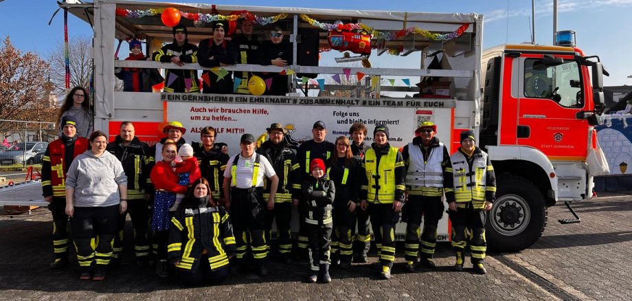 Feuerwehrleute beim Fastnachtsumzug vor einem Feuerwehrfahrzeug.