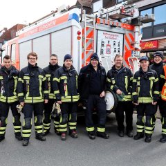 Einsatzkräfte der Feuerwehr vor einem Feuerwehrauto.