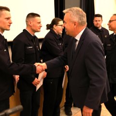 Der Bürgermeister und ein Feuerwehrmann gratulieren fünf in Reihe stehenden Feuerwehrleuten.