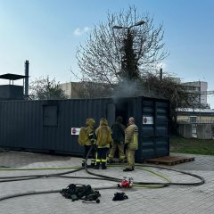 3 Atemschutzgeräteträger in ihrer PSA vor dem Realbrandcontainer.