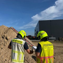 Feuerwehrleute in Schutzkleidung arbeiten gemeinsam an einer Übung im Bereich Technische Hilfeleistung am Bau.