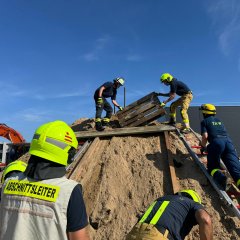 Feuerwehrleute in Schutzkleidung arbeiten gemeinsam an einer Übung im Bereich Technische Hilfeleistung am Bau.