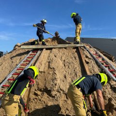 Feuerwehrleute in Schutzkleidung arbeiten gemeinsam an einer Übung im Bereich Technische Hilfeleistung am Bau.