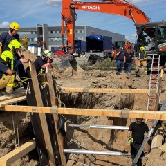Feuerwehrleute in Schutzkleidung arbeiten gemeinsam an einer Übung im Bereich Technische Hilfeleistung am Bau.