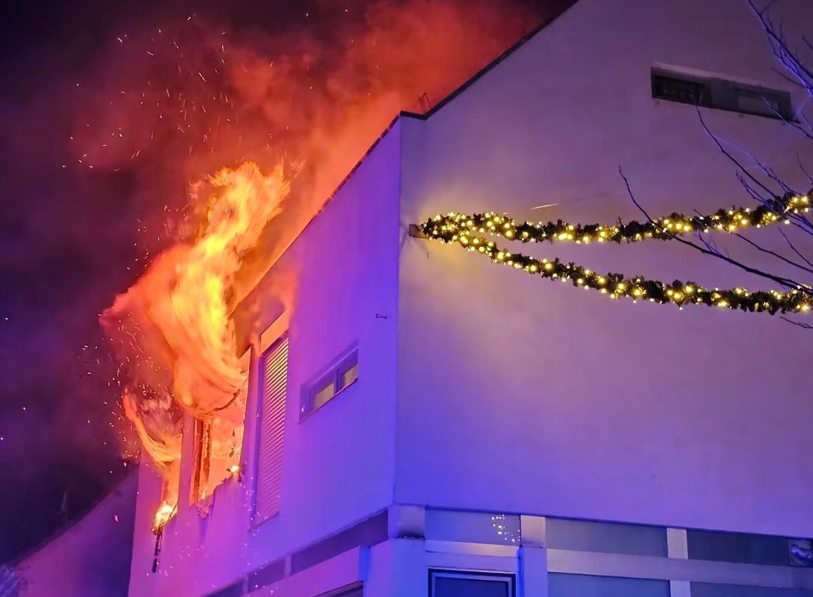 Flammen schlagen aus zwei Fenstern im 1. Stock eines Wohnhauses.