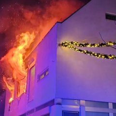 Flammen schlagen aus zwei Fenstern im 1. Stock eines Wohnhauses.