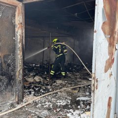 Ein Trupp unter Atemschutz löscht letzte Glutnester in einer Lagerhalle ab.