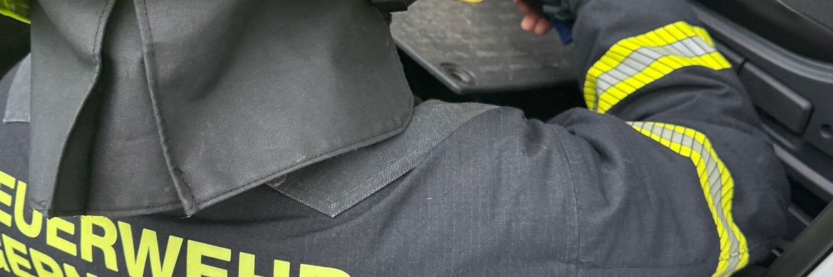 Eine Einsatzkraft sucht die Batterie im Fußraum eines verunfallten Fahrzeuges, um diese abklämmen zu können.