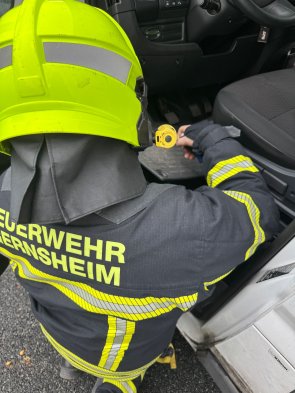 Eine Einsatzkraft sucht die Batterie im Fußraum eines verunfallten Fahrzeuges, um diese abklämmen zu können.