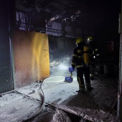 Brennender Unrat in einer Lagerhalle wird durch Feuerwehrkräfte abgelöscht.