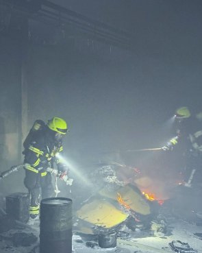 Brennender Unrat in einer Lagerhalle wird durch Feuerwehrkräfte abgelöscht.