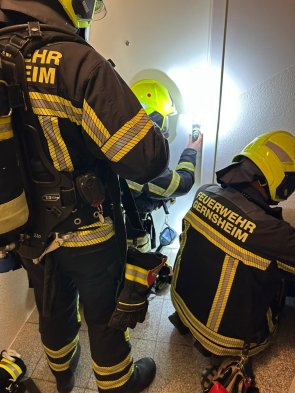 Feuerwehrkräfte versucht mittels Türöffnungswerkzeug eine Wohnungstüre gewaltfrei zu öffnen.