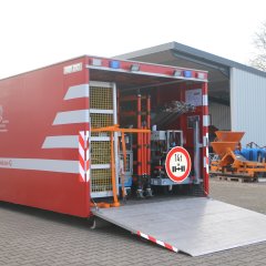 Ein geöffneter Abrollbehälter Dekontamination Geräte (AB-Dekon-G). Im Hintergrund eine Fahrzeughalle.