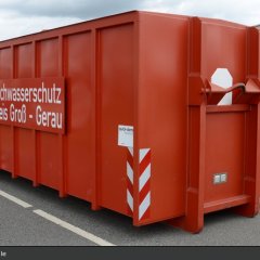 Roter Abrollbehälter der Feuerwehr für Hochwasserschutz (AB-HWS-1).