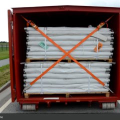 Roter Abrollbehälter der Feuerwehr für Hochwasserschutz (AB-HWS-1). Geöffnete Tür mit Blick auf Dammbaumaterial.