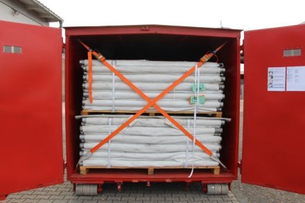 Roter Abrollbehälter der Feuerwehr für Hochwasserschutz (AB-HWS-1). Geöffnete Tür mit Blick auf Dammbaumaterial.