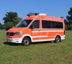 Rotes Feuerwehrfahrzeug, ein Einsatzleitwagen (ELW1), steht auf einer Rasenfläche.