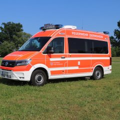 Rotes Feuerwehrfahrzeug, ein Einsatzleitwagen (ELW1), steht auf einer Rasenfläche.