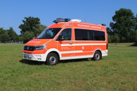 Rotes Feuerwehrfahrzeug, ein Einsatzleitwagen (ELW1), steht auf einer Rasenfläche.