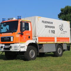 Rotes Feuerwehrfahrzeug, ein Gerätewagen Logistik (GW-L 2), steht auf einer Rasenfläche.