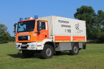 Rotes Feuerwehrfahrzeug, ein Gerätewagen Logistik (GW-L 2), steht auf einer Rasenfläche.
