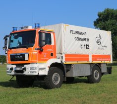 Rotes Feuerwehrfahrzeug, ein Gerätewagen Logistik (GW-L 2), steht auf einer Rasenfläche.