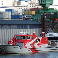 Rotes Feuerwehrboot mit Namen Hecht, ein Hilfeleistungslöschboot (HLB), hat im Sportboothafen an einer Bootshalle festgemacht.