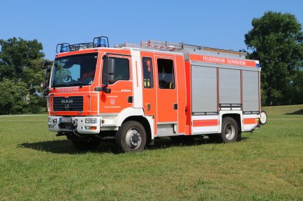 Rotes Feuerwehrfahrzeug, ein Hilfeleistungslöschfahrzeug (HLF 20-16), steht auf einer Rasenfläche.