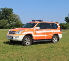 Rotes Feuerwehrfahrzeug, ein Kommandowagen (KdoW), steht auf einer Rasenfläche.